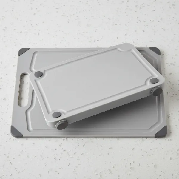 Detailed view of a plastic cutting board highlighting its juice groove, non-slip feet, and handle.